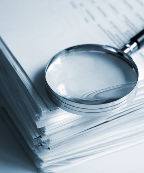 Magnifying glass sitting on top of stack of white papers