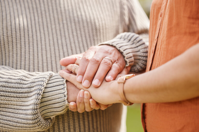 Women holding hands comfortingly