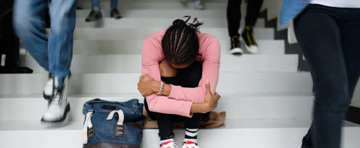 Depressed young student sitting on floor at college or university