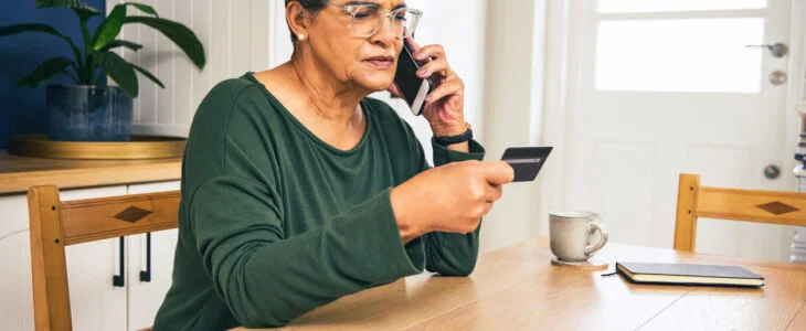 Shot of a mature woman sitting alone at home and looking confused while using her cellphone for online banking